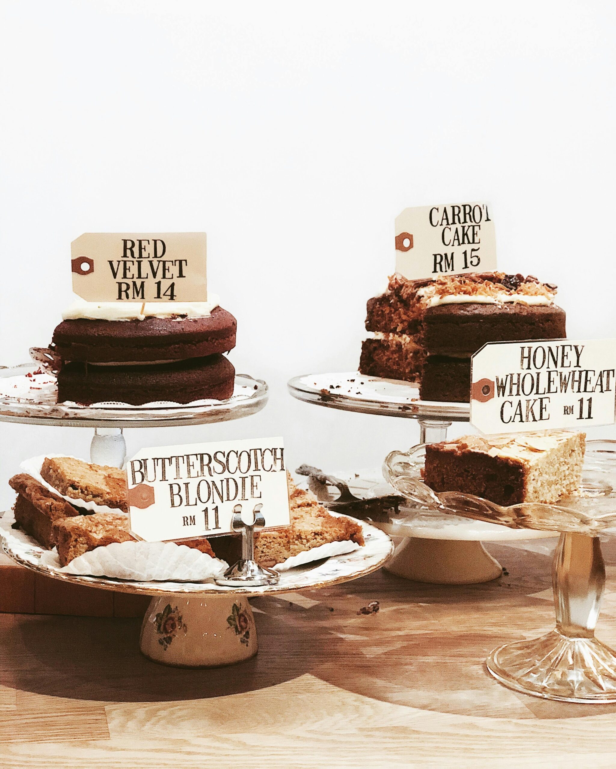 A variety of delicious cakes with price tags displayed on elegant stands.