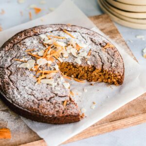 A rustic carrot cake with almonds on a wooden board, perfect for dessert.