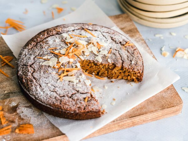 A rustic carrot cake with almonds on a wooden board, perfect for dessert.